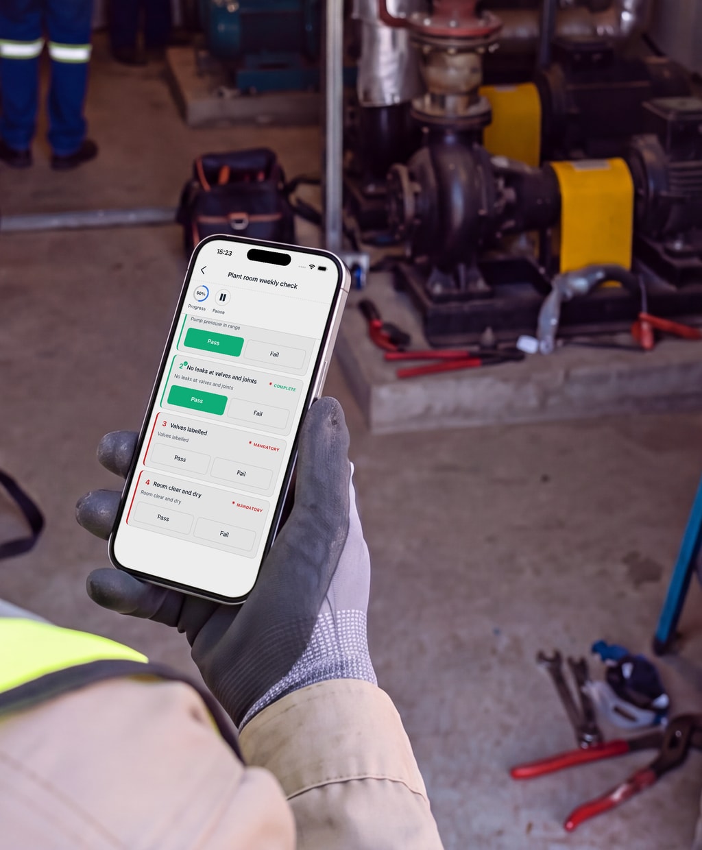 A technician working through a check on the PremHQ app in a plant room.