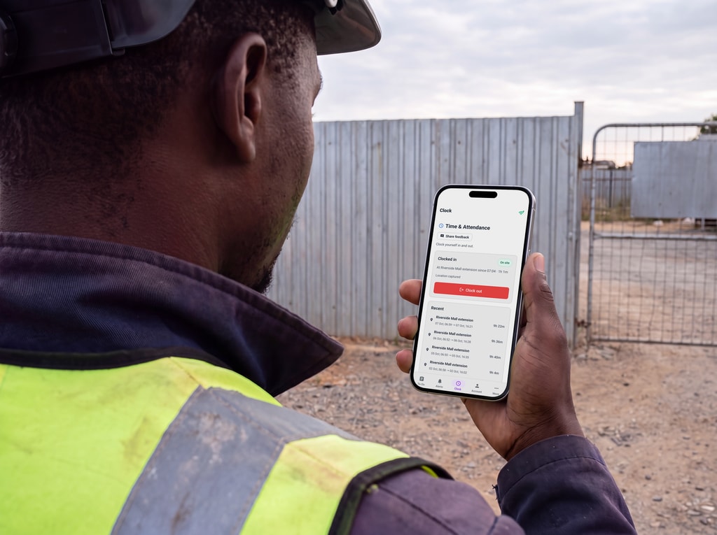A worker clocks himself in on his own phone at the site gate.