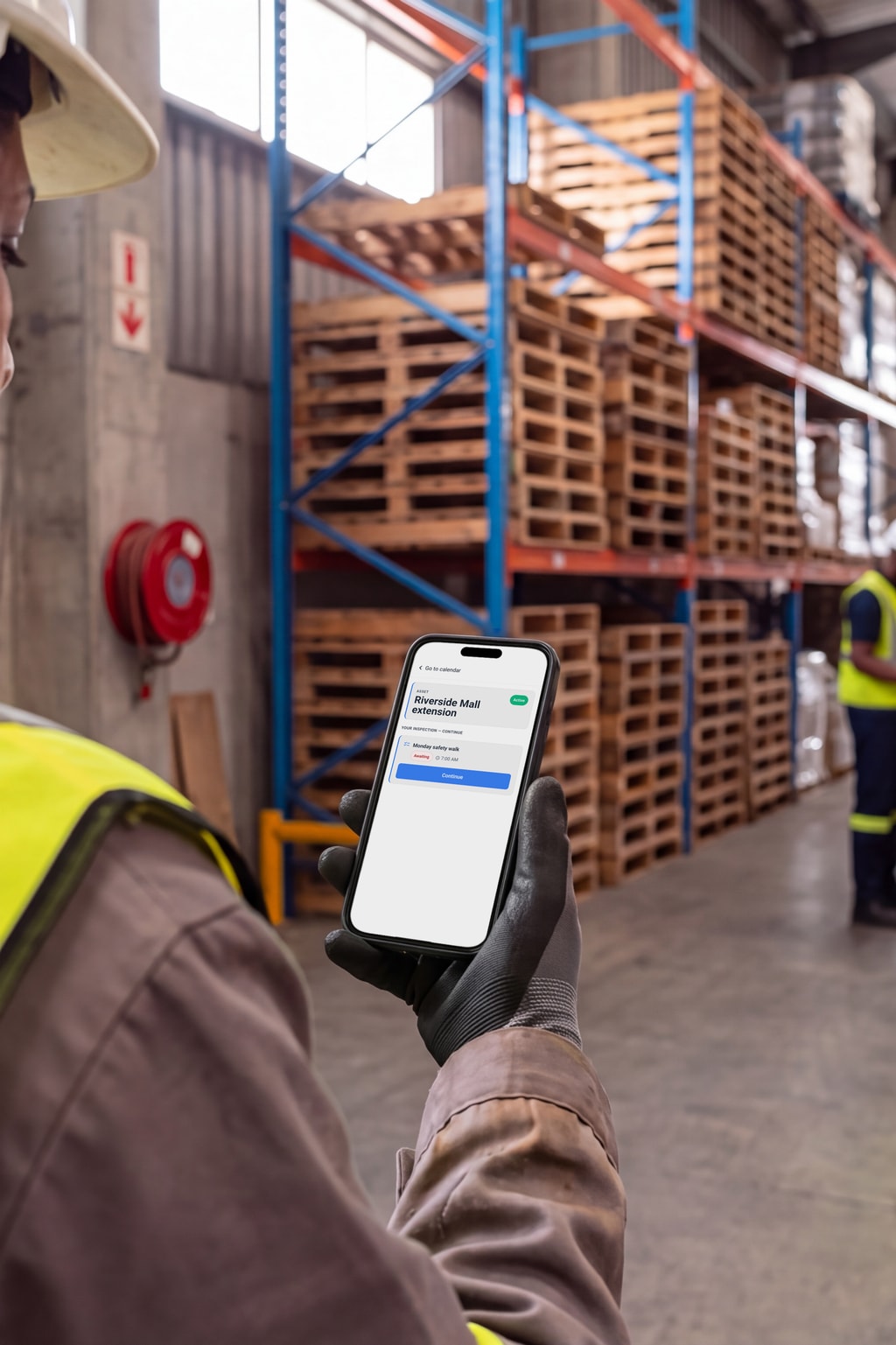 Two site audits under way on the PremHQ app: in a warehouse aisle, and at a building under scaffolding.